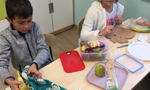 Zdjęcie przedstawia uczniów klasy 2 podczas przygotowywania sałatki owocowej